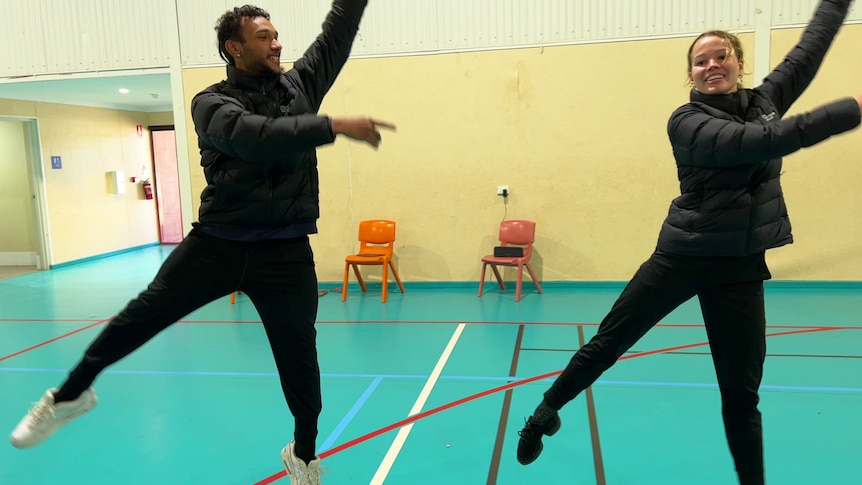 A man and woman dancing on a blue indoor basketball court