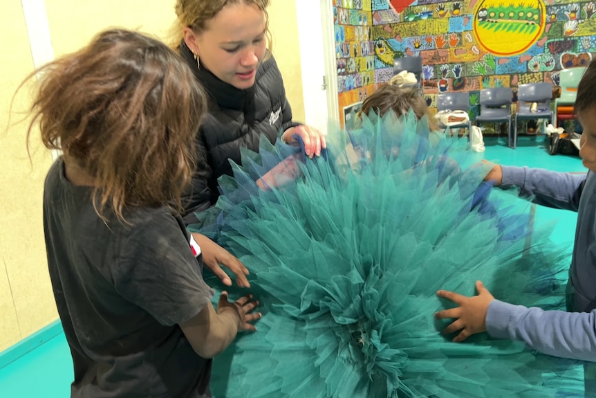 A teacher and students examine a green tutu