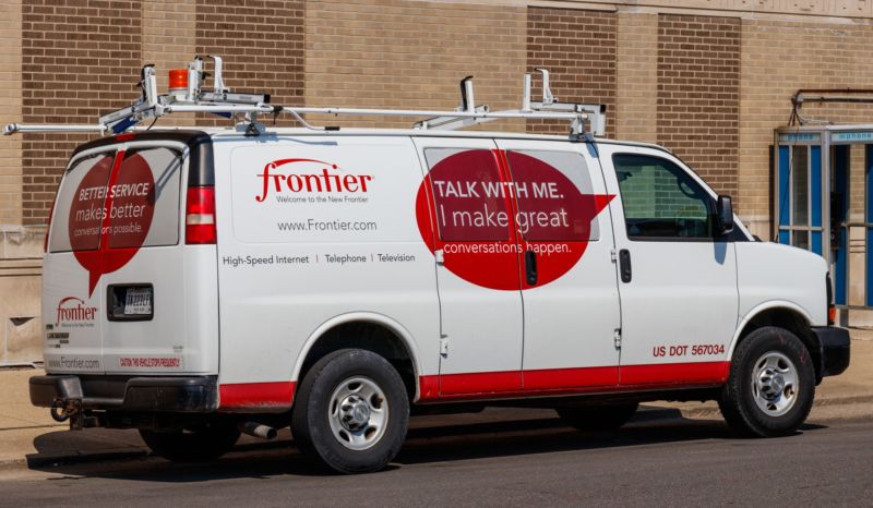 A Frontier telecom service car is parked in front of a building.